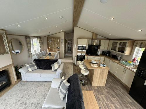 a living room with a couch and a kitchen at Golden Anchor - The Oakland Lodge - Coastal Caravan Breaks in Chapel Saint Leonards
