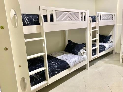 Ramble stay Hostel Bur Dubai في دبي: سريرين بيض بطابقين في غرفة مع