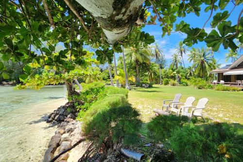 two white chairs sitting on a beach near the water at Villa Tiarenui in Maharepa