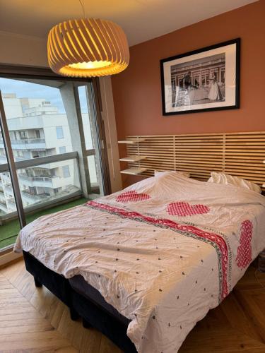 une chambre avec un lit et une grande fenêtre dans l'établissement Appartement cosy vu Tour Eiffel, à Courbevoie