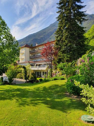 ein großes Gebäude inmitten eines grünen Gartens in der Unterkunft Residenze Mathilda in Schlanders