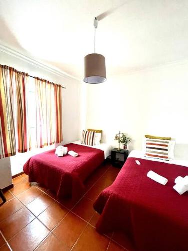 a room with two beds with red sheets in it at A Casa D'Avó Chica - Alentejo in Portel