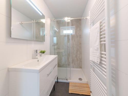 La salle de bains blanche est pourvue d'un lavabo et d'une douche. dans l'établissement Modern chalet with a fireplace near the Oosterschelde, à Wemeldinge