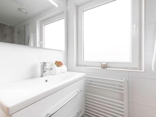 a white bathroom with a sink and a mirror at Modern, high-quality chalet with WiFi in Wemeldinge