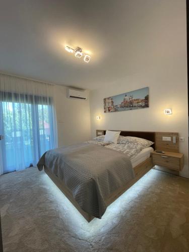 een slaapkamer met een bed en een groot raam bij Szil-Luxury Apartman in Zamárdi