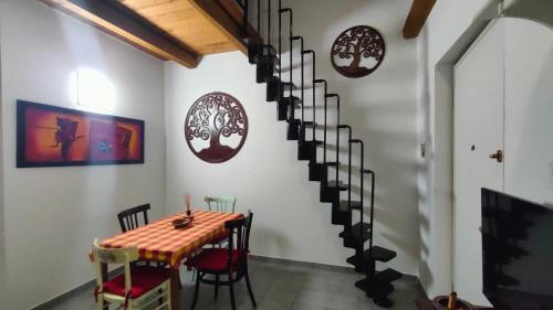 a dining room with a table and a spiral staircase at Case sul ruscello in San Sebastiano Da Po