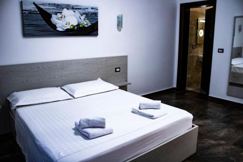 een slaapkamer met een wit bed en 2 handdoeken bij Villa La Quiete - Adults only in Sarandë