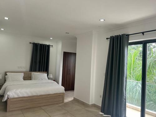 ein Schlafzimmer mit einem Bett und einem großen Fenster in der Unterkunft Stay Play Away Residences - Luxury 4 bed, Airport Residential, Accra in Accra