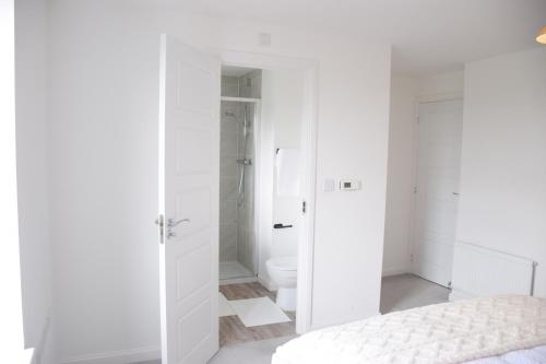 a white bedroom with a shower and a bed at Orient Oasis Yarm in Yarm