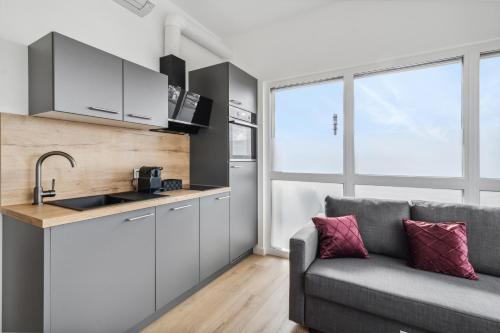 a living room with a couch and a kitchen at SUITE4ME - Moderne Apartments I Küche I Balkon I Waschmaschine in Dietzenbach