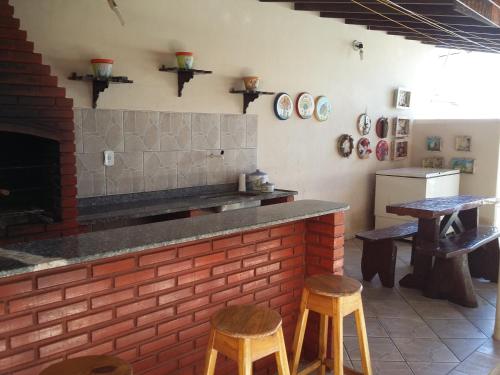 a kitchen with two stools and a counter with a brick wall at Pousada Pé de Caju in Alcobaça