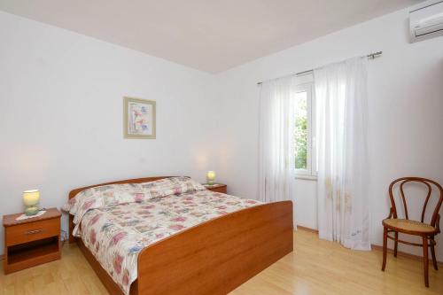a bedroom with a bed and a chair and a window at Apartments Goga in Orebić