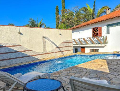 a swimming pool with two chairs and a house at Incrivel casa com lazer completo e WiFi -Ibiuna SP in Ibiúna
