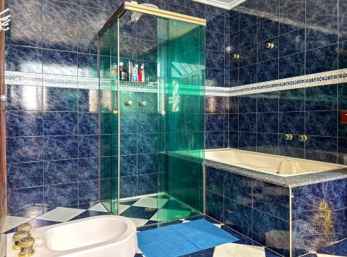 a blue tiled bathroom with a toilet and a tub at Incrivel casa com lazer completo e WiFi -Ibiuna SP in Ibiúna