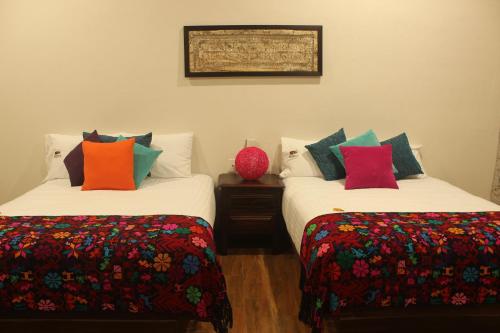 two beds with colorful pillows in a room at Hotel Boutique La Casona de Don Porfirio in Jonotla
