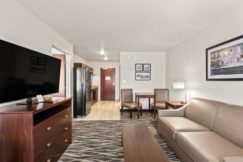 a living room with a couch and a tv and a table at Cobblestone Hotel & Suites - Cullman in Cullman
