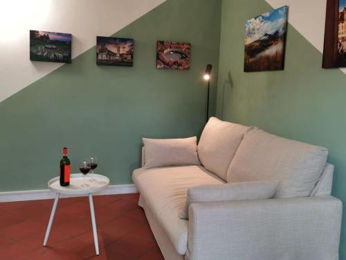 a living room with a couch and a table with a bottle of wine at CASA ARYA - Independent House - Near the Walls in Lucca