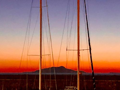 two masts of two sailboats in front of a sunset at Bilocale panoramico “Lo sguardo” in Massa Lubrense