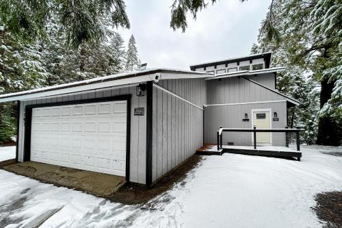 a garage with two doors and snow on the ground at Whispering Trees in Fish Camp