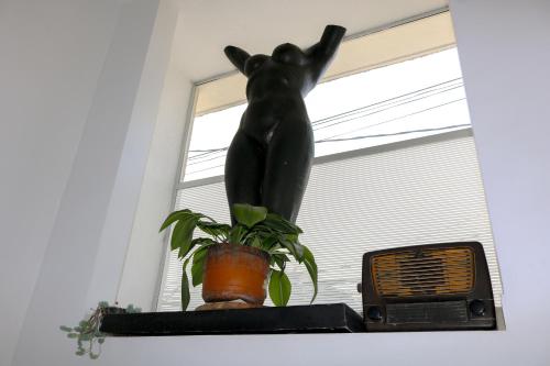 a statue of a cat sitting on a shelf next to a plant at Hotel Casa Botero 202 in Bogotá