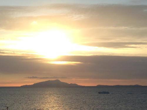 a sunset over the ocean with a mountain in the distance at Bilocale panoramico “Lo sguardo” in Massa Lubrense