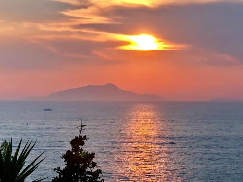a sunset over the ocean with a mountain in the background at Bilocale panoramico “Lo sguardo” in Massa Lubrense