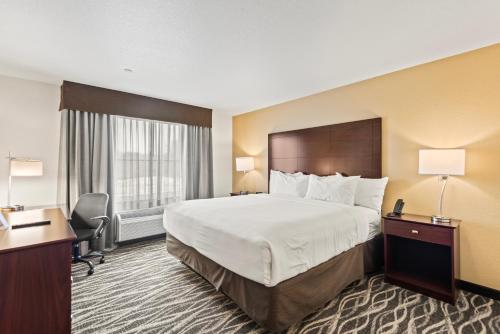 a hotel room with a large bed and a desk at Cobblestone Hotel & Suites - Cullman in Cullman