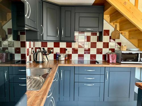 une cuisine avec des armoires bleues et un évier dans l'établissement Appartement plein sud - Thônes, à Thônes