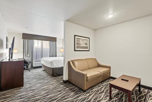 a hotel room with a bed and a couch and a chair at Cobblestone Hotel & Suites - Cullman in Cullman