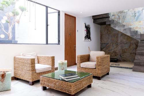 a living room with wicker chairs and a glass table at Urban Puebla by Grupo Amber in Puebla