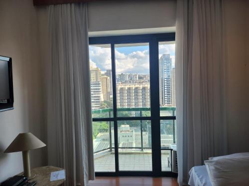 a room with a window with a view of a city at Apart hotel Champagnat in Belo Horizonte