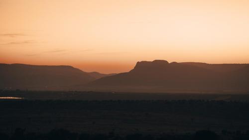 a sunset with mountains in the distance at Umkhaya lodge in Mkuze