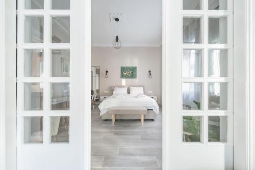 ein weißes Schlafzimmer mit einem Bett und zwei Fenstern in der Unterkunft Iris Peacock's The Garden in Piräus