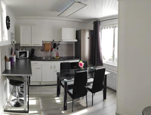 una cocina con mesa y sillas y una cocina con armarios blancos. en Maison plein pied 1, en Hérin