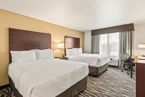 a hotel room with two beds and a desk at Cobblestone Hotel & Suites - Cullman in Cullman