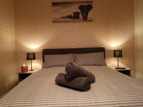 a bedroom with a bed with a towel on it at MossBank House Luton Airport in Luton