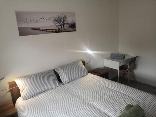 a bedroom with a bed with two pillows and a picture on the wall at MossBank House Luton Airport in Luton