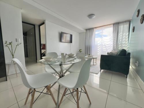 a dining room with a glass table and white chairs at Emy's City Center Flat at 77 on Independence in Windhoek