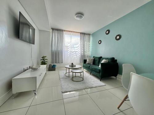 a living room with a green couch and a table at Emy's City Center Flat at 77 on Independence in Windhoek