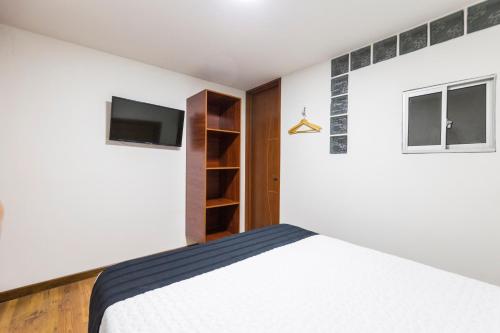 ein Schlafzimmer mit einem Bett und einem TV an der Wand in der Unterkunft Hotel Casa Botero 204 in Bogotá