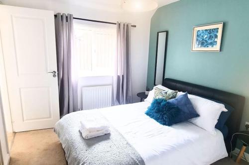 a bedroom with a white bed with blue walls at Convenient & cosy 3 bed house in Newport