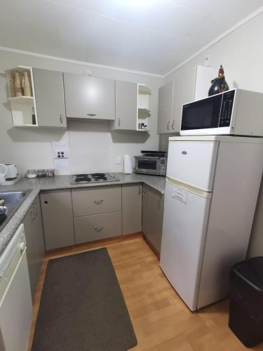 a kitchen with white cabinets and a white refrigerator at On Tate in Waitara