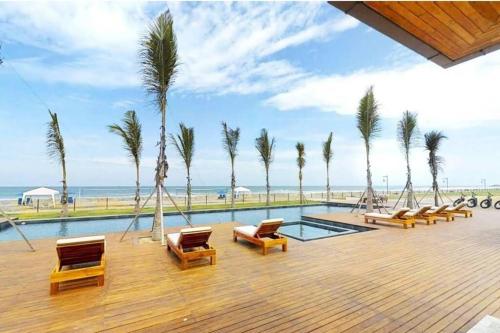 uma piscina com cadeiras e palmeiras e o oceano em Ecusuites Karibao Room 3 Genius playas em Playas