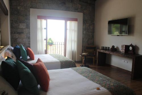 a hotel room with two beds and a television at Hotel Boutique La Casona de Don Porfirio in Jonotla