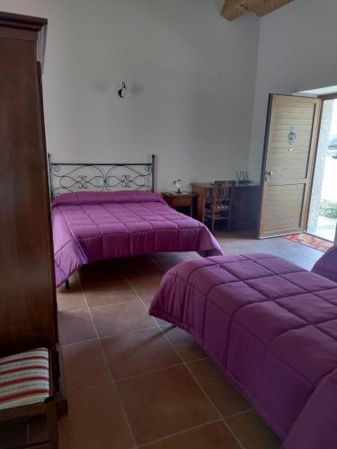 two beds in a room with purple sheets at Tenuta Barone in Duronia