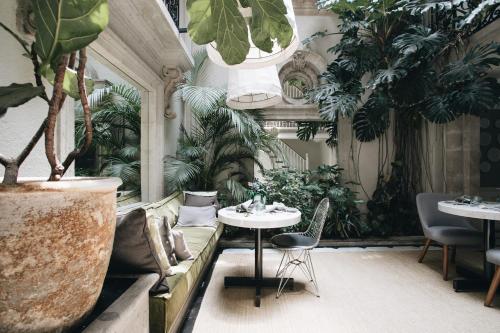 een kamer met een bank en tafels en planten bij Nima Local House Hotel & Spa in Mexico-Stad