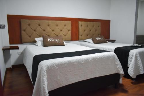 Duas camas num quarto com lençóis brancos e almofadas castanhas em Hotel Casa Botero 205 em Bogotá