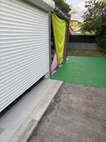 a garage with a green floor and a house at Bas de villa ensoleillé ventilé in Morne-à-lʼEau