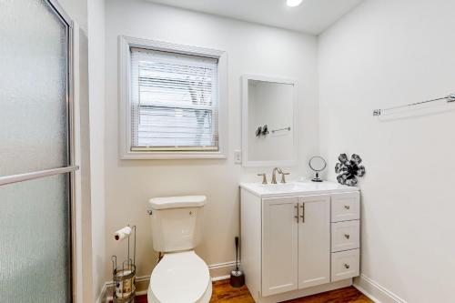 a bathroom with a toilet and a sink and a window at Orange Street Haven in Wilmington