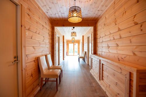 a hallway in a log cabin with chairs and a chandelier at Gladheimar Guesthouse in Blönduós